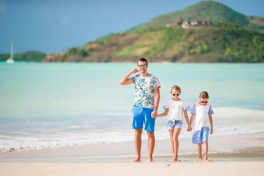 Un padre pasea por una playa mediterránea de la mano de sus dos hijas
